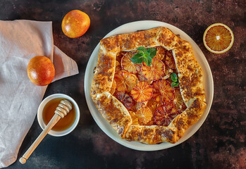 Homemade red blood orange galette with mint and honey. Fruit bakery. Healthy vegetarian dessert. Open pie, orange tart.