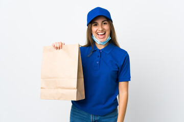 Food delivery woman and protecting from the coronavirus with a mask over isolated white background smiling a lot