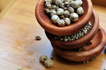 pepper, cardamom, and cinnamon in a wooden bowl on a wooden tray plus garlic and salt. close up with selective focus