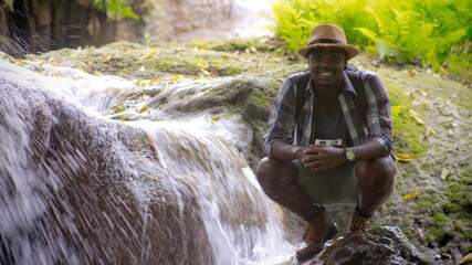 African traveler man sitting and relaxing freedom with waterfall.16:9 style