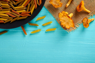Raw pasta on a black plate and mushrooms, top view, copy space