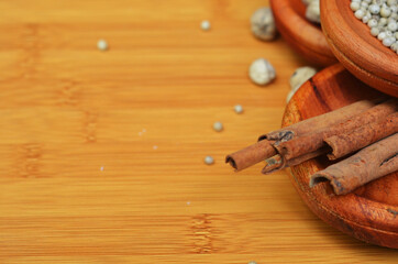 pepper, cardamom, and cinnamon in a wooden bowl on a wooden tray. close up with selective focus