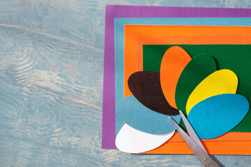Cut out colored Easter paper eggs, pattern and scissors on colorful paper on a blue wooden table, copy space