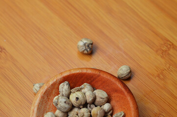 cardamom in a wooden bowl on a wooden tray. close up with selective focus