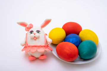Happy Easter concept. Hand-painted Easter eggs and a hand-made plasticine bunny in a pink skirt on white