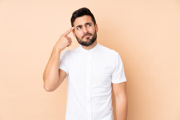 Caucasian handsome man isolated on beige background making the gesture of madness putting finger on the head