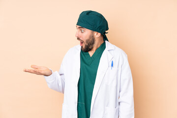 Surgeon man isolated on beige background holding copyspace imaginary on the palm