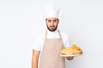 Male baker holding a table with several breads isolated on white background sad