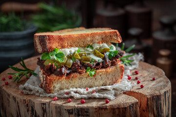 Sandwich with pulled pork and pickles with sauce.