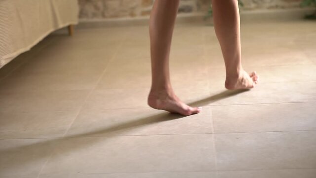 Barefoot woman steps carefully on tiptoes and leaves the room