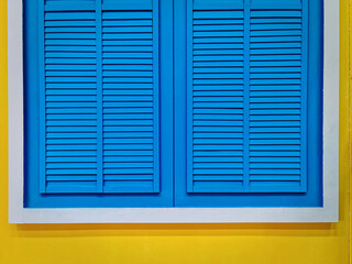 Blue Vintage Wooden Window with White Frame on Vivid Yellow Wall