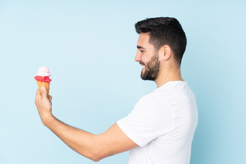 Caucasian man with a cornet ice cream isolated on blue background with happy expression