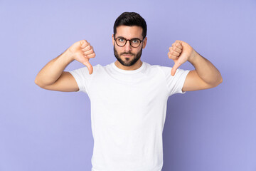 Caucasian handsome man over isolated background showing thumb down with two hands