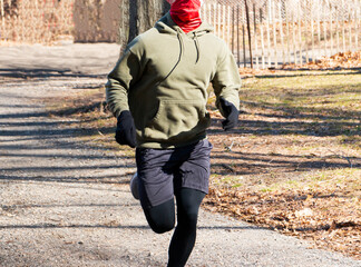 Runner wearng gater face mask for protection running in the woods