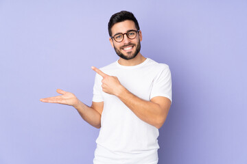 Caucasian handsome man over isolated background holding copyspace imaginary on the palm to insert an ad