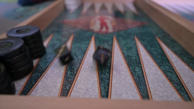 Slow motion video shows a hand throwing dices on a backgammon board. Selective focus.