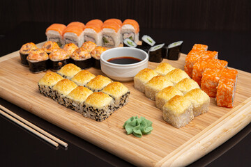 Big sushi set on light wooden dish isolated on black background