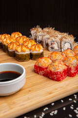 Big sushi set on light wooden dish isolated on black background