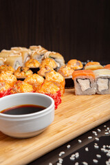 Big sushi set on light wooden dish isolated on black background