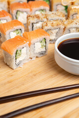 Big sushi set on light wooden dish isolated on black background