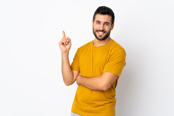 Young handsome man with beard isolated on white background happy and pointing up