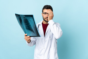 Professional traumatologist holding radiography isolated on blue background covering a eye by hand