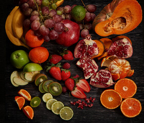 Top view of fresh multicolor fruits and vegetables on dark old wood. Different fruits and vegetables for eating healthy.