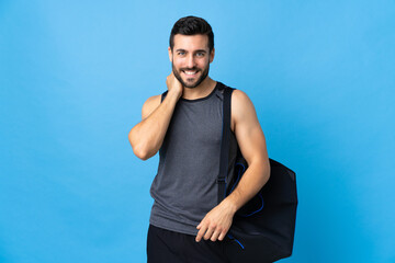 Young sport man with sport bag isolated on blue background laughing