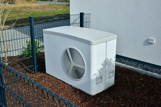 Luftwärmepumpe/Klimaanlage für Heizung und Warmwasser vor einem neu gebauten Wohnhaus in einem Neubaugebiet