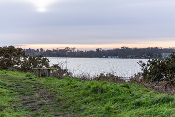 A rural wooden bench overlooking a beautiful view of the river Deben in the Suffolk countryside