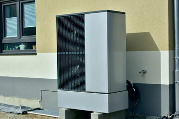 Luftwärmepumpe/Klimaanlage für Heizung und Warmwasser vor einem neu gebauten Wohnhaus in einem Neubaugebiet