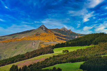 landscape with mountains and clouds and green and orange vegetation.