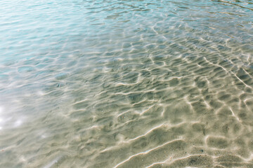 Sand shines through the sea waves, blue ocean, background