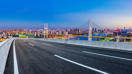 Asphalt highway and city skyline with bridge at night in Shanghai,China.