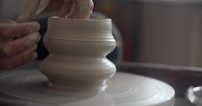 Potter shapes a jug on a potter's wheel, video from pottery workshop, ceramist makes ceramics in slow motion, 4k 60p Prores HQ 10 bit