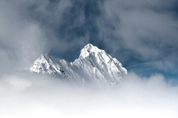Fototapeta na wymiar Snowy snow-capped rock mountain peaks protrude from fog soup with a downward white gradient