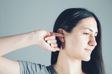 Fototapeta premium Close-up woman trying to clean her ear with her finger