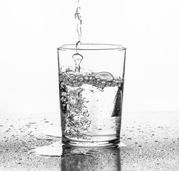 Water being poured into a glass. White background..
