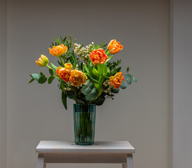 A bouquet of peach and orange colored roses on a small table.
