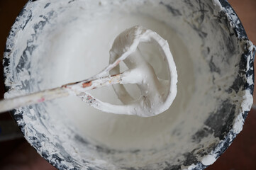 Mixer for building mixes in white liquid putty on the background of ready-made material for application to walls