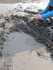creative child making sand sculpture with two hands on the beach design for relaxation lifestyle