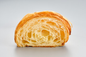Fresh baked croissant unfilled cutaway on a light grey backgroundon. Airy porous structure of a...