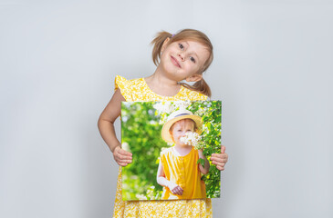 A Little girl holding a photobook with her photographs in her handspt