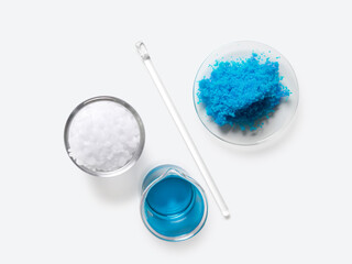 Inorganic chemical placed next to the Stirring Rod on white laboratory table. Copper(II) sulfate, Microcrystalline wax, alcohol. Chemical ingredient for Cosmetics and Toiletries product. Top View