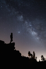 Fototapeta premium Silueta de una persona de noche con la vía láctea en el cielo estrellado