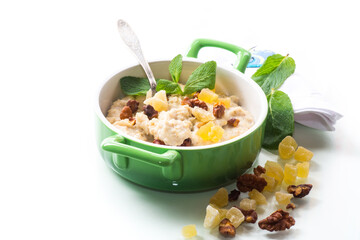 cooked boiled sweet oatmeal with nuts and candied fruits in a bowl