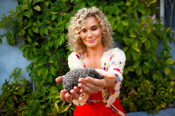 Portrait of woman holding hedgehog in wildlife