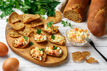 Rye bread chips. A delicious snack of whole-grain slices bread with seeds and a salad of salted or smoked fish (salmon or trout), eggs, parmesan cheese and parsley. Selective Focus