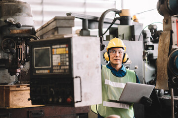 Fototapeta na wymiar Work at factory.Asian worker man working in safety work wear with yellow helmet using digital laptop computer.in factory workshop industry machine professional