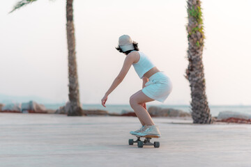 Asian women surf skate or skateboard outdoors on beach miami sunset.